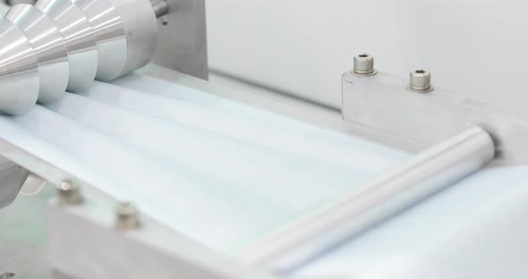 Face Mask Fabric Running Through Reel Of Pleating Machine. Creating Pleats Of Surgical Mask. slider alt