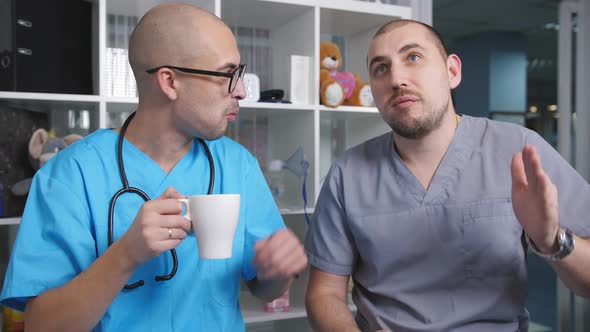 Two Men Drinking Coffee and Talking During a Break in the Staff Lounge