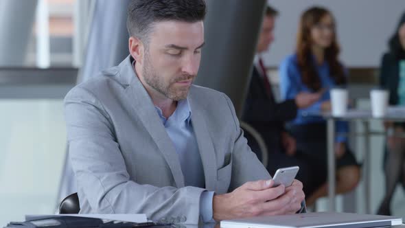 Young businessman using cell phone in office lobby