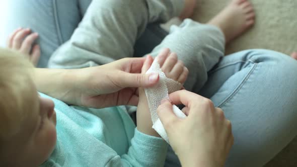 A woman heals the hand of baby, bandaging it with a bandage alt