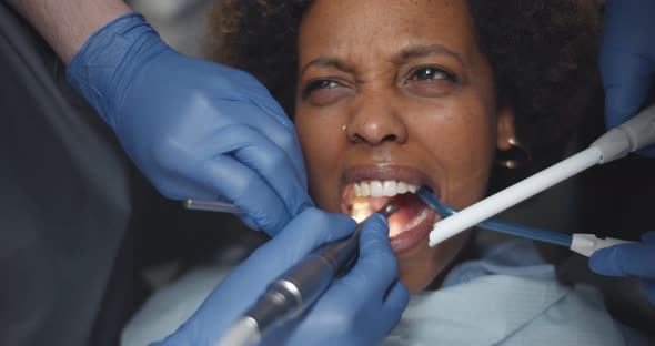 Close Up of Dentist's Hands and Equipment Working on Stressed Woman Teeth alt