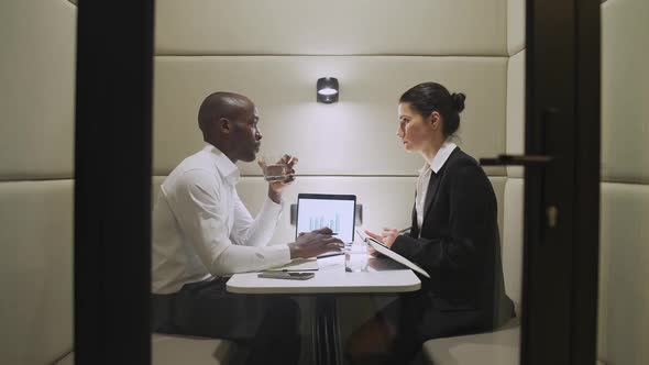 African Businessman and a Female Financier Discuss Financial Work Matters While Sitting in the alt
