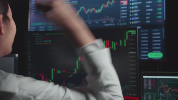 Asian Female Stock Market Broker Working On Computer And Celebrating With Analysing Graphs alt