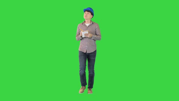 Construction Worker in a Hardhat Takes Some Notes While Walking on a Green Screen Chroma Key