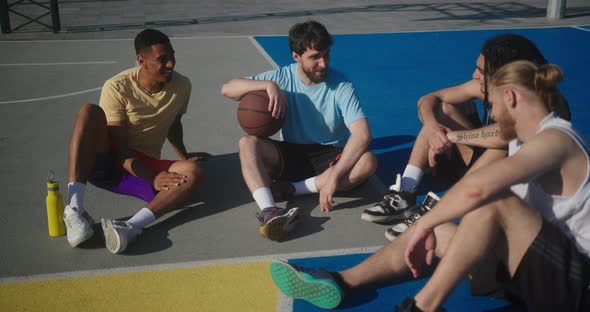 Sportsmen Discuss Topics Sitting on Basketball Court Closeup