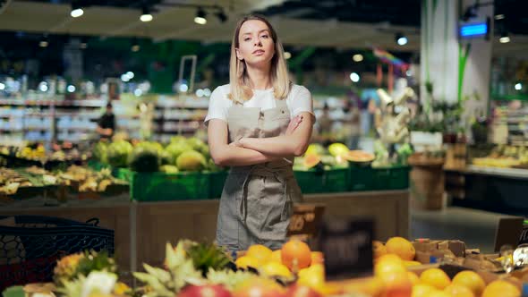 portrait of saleswoman, woman smiling and looking at camera in supermarket.  alt