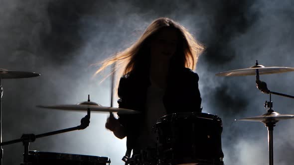 Specially Trained Girl Plays the Drums. Black Smoke Background. Silhouette alt