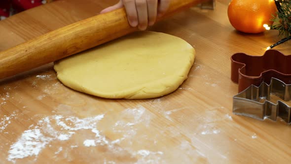 A little girl rolls out an adze for making Christmas dessert. Christmas gingerbread and cookies. alt