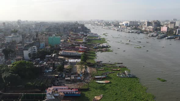 Aerial: ship wrecking dockyard at Buriganga river bank with cityscape - drone flying forward shot alt