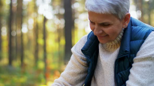 Senior Woman Picking Mushrooms in Autumn Forest alt