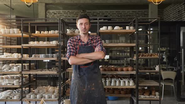 Attractive Male Potter Crossing Hands and Looking to Camera in the Pottery alt