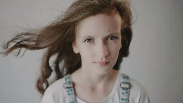 Portrait of a beautiful girl with fluttering hair. Slowmotion of flying hair.	