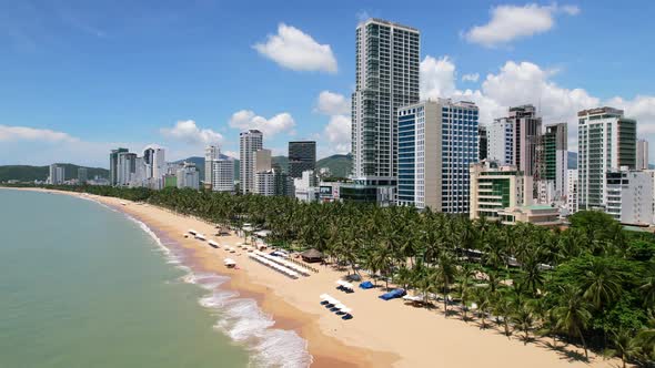 wide aerial view  of an asian beach town on a sunny day as ocean waves crash onto the prestine and e alt