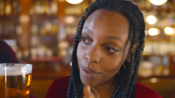 Close Up of Young African Woman Making Toast and Clinking Beer Glasses with Friends in Bar alt