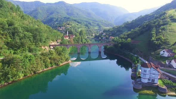Flying over river and old stone bridge in Bosnia alt