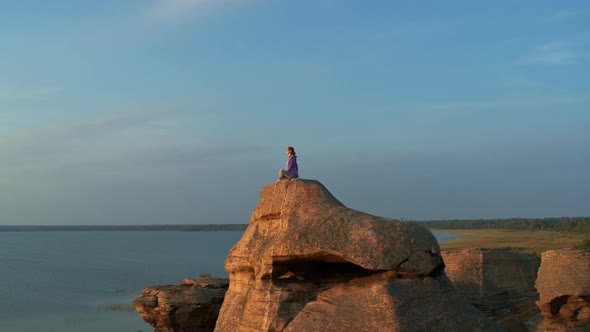 A Girl is Doing Fitness on a Hill on the Lake Shore