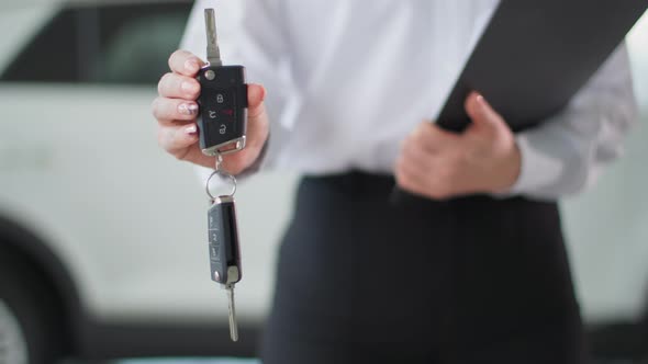 Business Car Young Female Manager Holds Keys in Her Hands to New Automobile Close Up Plan