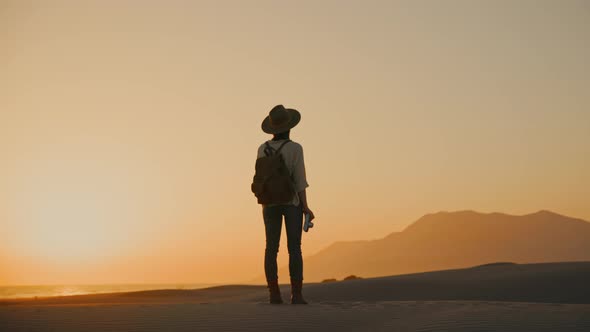 A young girl with a retro camera looking at the mountains alt