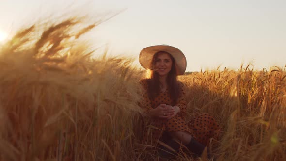 Pregnant woman in the rays of the sunset in the field alt