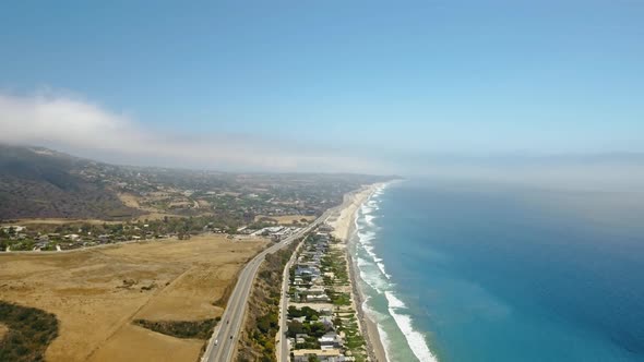 Ocean and coast with a road and cars, a settlement and fields in Malibu, California, USA alt
