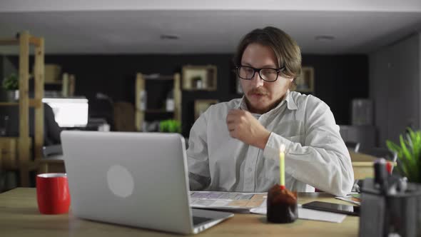 Sad and Tired Businessman Celebrating a Lonely Birthday in the Office alt