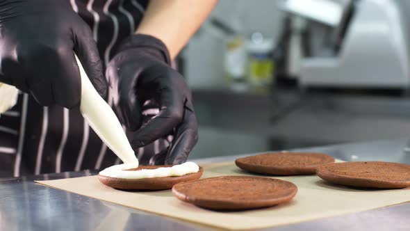 Pastry Chef is Filling Cookies with Cream and Jam Making Small Cakes