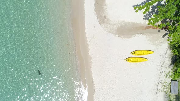 Wide drone shot of two yellow kayaks on the beach. Koh Kood, Thailand. alt