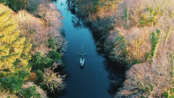 Aerial shot boat driving along river in Autumn alt
