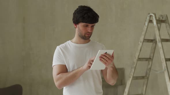 Man Stand in New Apartment Using Tablet Choosing New Design of House alt