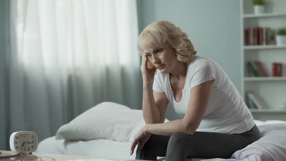 Menopause. Adult Female Sitting on Bed and Suffering From Migraine, Health alt