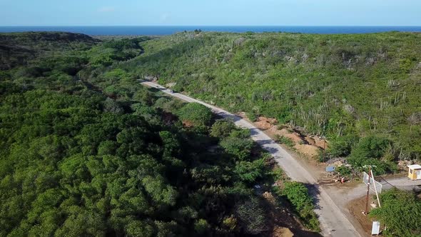Dolly in aerial view of a single car driving to Kanoa Beach, a rare surfer's beach on the Dutch isla alt