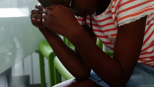 Upset girl sitting on chair in corridor alt