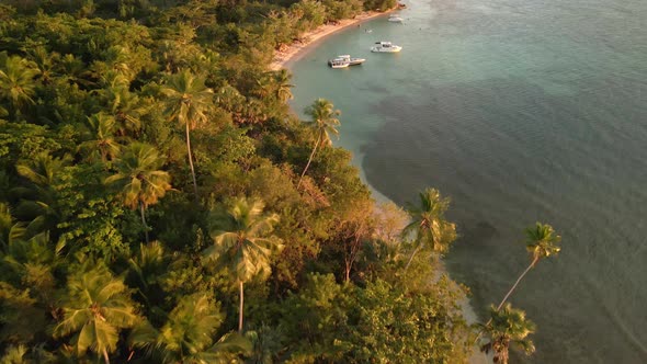 Flying drone on top of boats on the beach during sunset time alt
