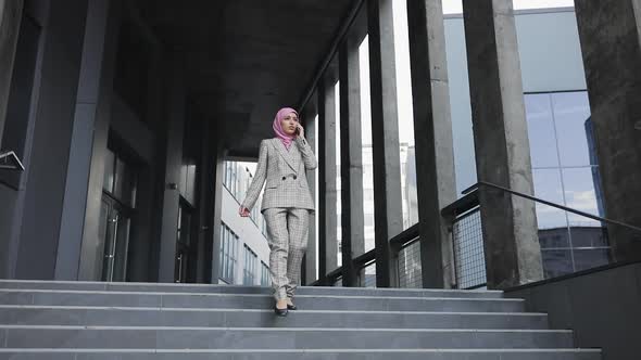 Young Beautiful Muslim Serious Woman Wearing Hijab Headscarf Walking Down Stairs Near Futuristic
