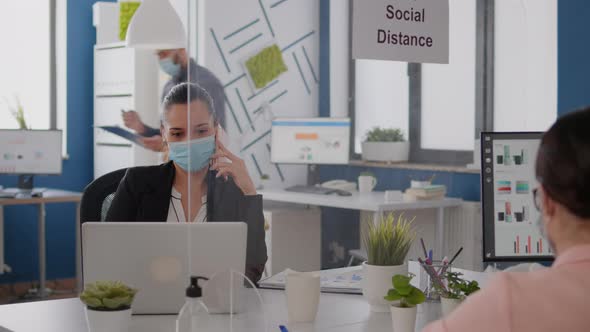 Woman with Protective Face Mask Working on Laptop Computer in Company Office alt