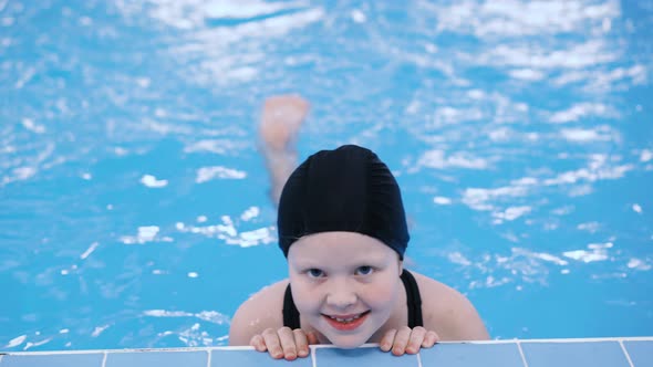 Swimming Lessons for Children in the Pool - Beautiful Fair-skinned Girl Swims in the Water