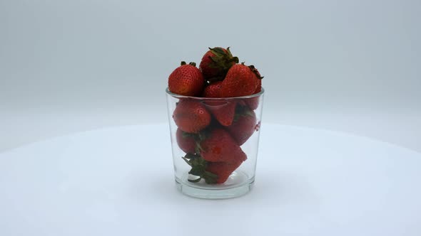 Strawberries in a clear glass rotating on a white background. Strawberry ripe season