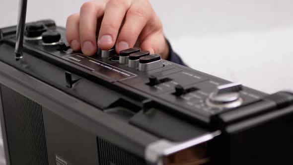 Male Hand Presses Play Button on Retro Tape Recorder with Antenna alt