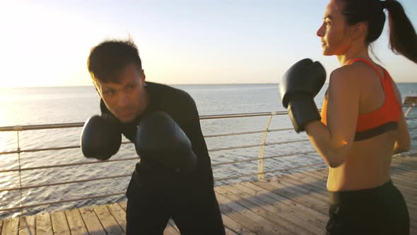 Young Female in Sport Clothes is Boxing with Her Professional Coach alt