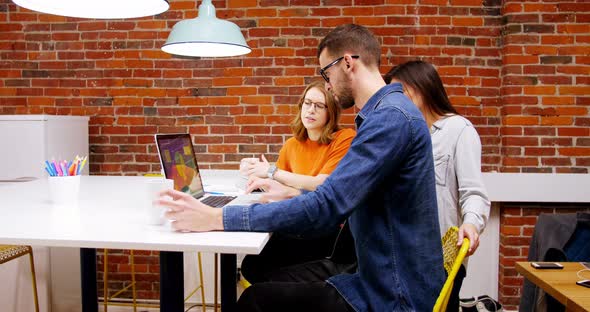 Group of executives discussing over laptop in the conference room alt