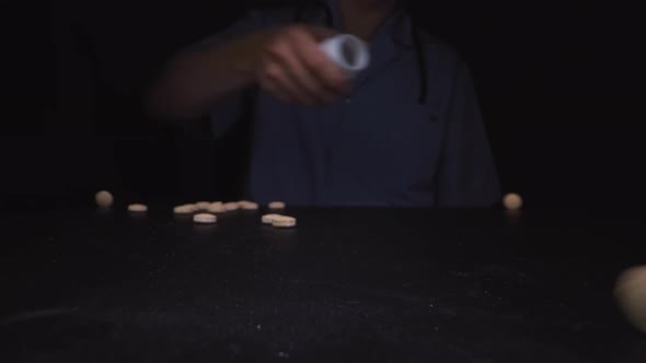 Person Pours Beige Drug Tablets Onto Black Surface Closeup alt