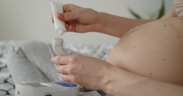 Young Pregnant Woman Applies Ultrasound Transmission Gel to a Doppler Transducer alt