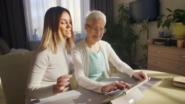 Cheerful Woman and Grandmother Using Digital Tablet Together