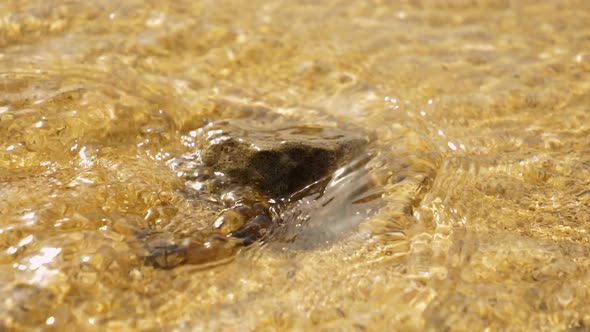 Closeup Shot of a Small Rock By the Beach Being Run Over by Waves