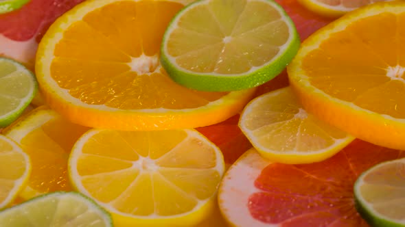 Close Up Orange Grapefruit Lemon and Lime Fruit Slices on Rotating Surface