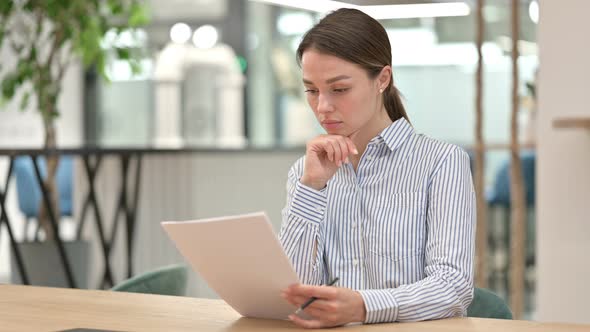Focused Young Woman Reading Documents in Office  alt