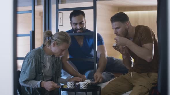 Portrait of Relaxed Multiracial Male Friends Celebrating Birthday in Inn or Hostel. Three Caucasian alt