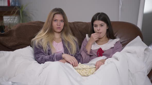Front View Two Young Women Discussing Show Watching TV Throwing Popcorn to Camera alt