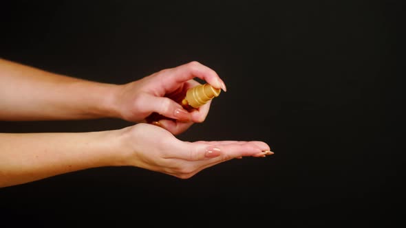 Female Hands Pushing Dispenser on Black Background Using Liquid Soap alt