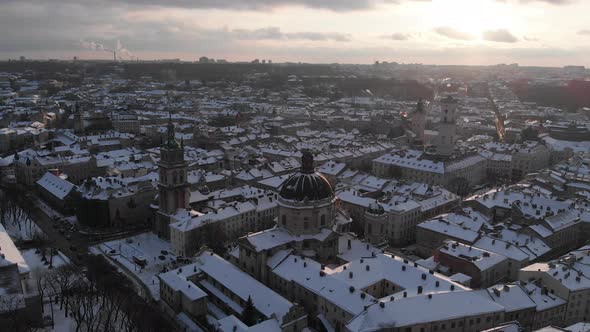 Aerial shot of Old City Lviv cowered by snow with churches and cathedrals. alt